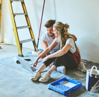 A couple sits on the floor taking a break from interior painting